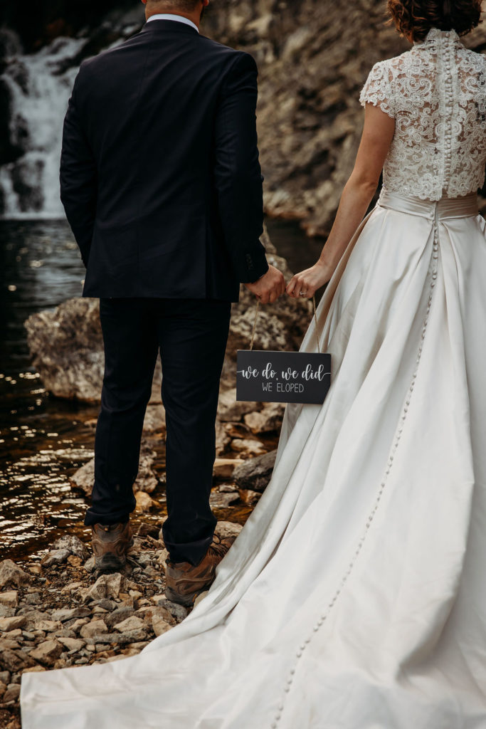 couple holding sign that says we do, we did, we eloped