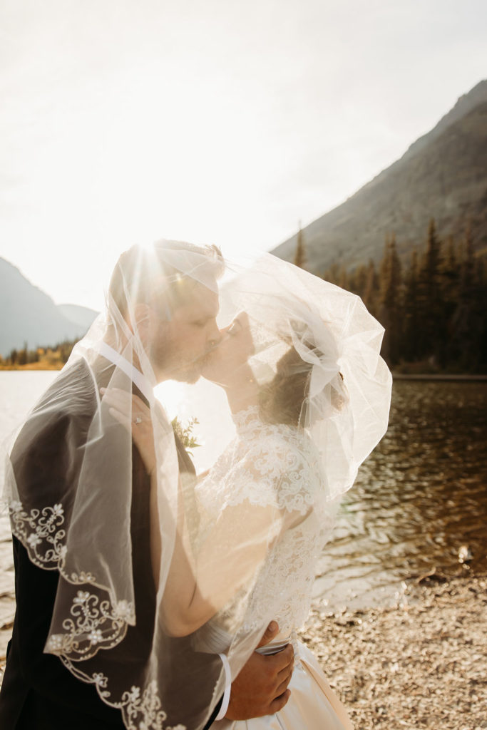 couple posing under wedding veil after glacier national park elopement