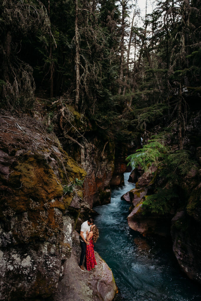 Couple posing for steamy engagement photos in Glacier National Park at Lake McDonald