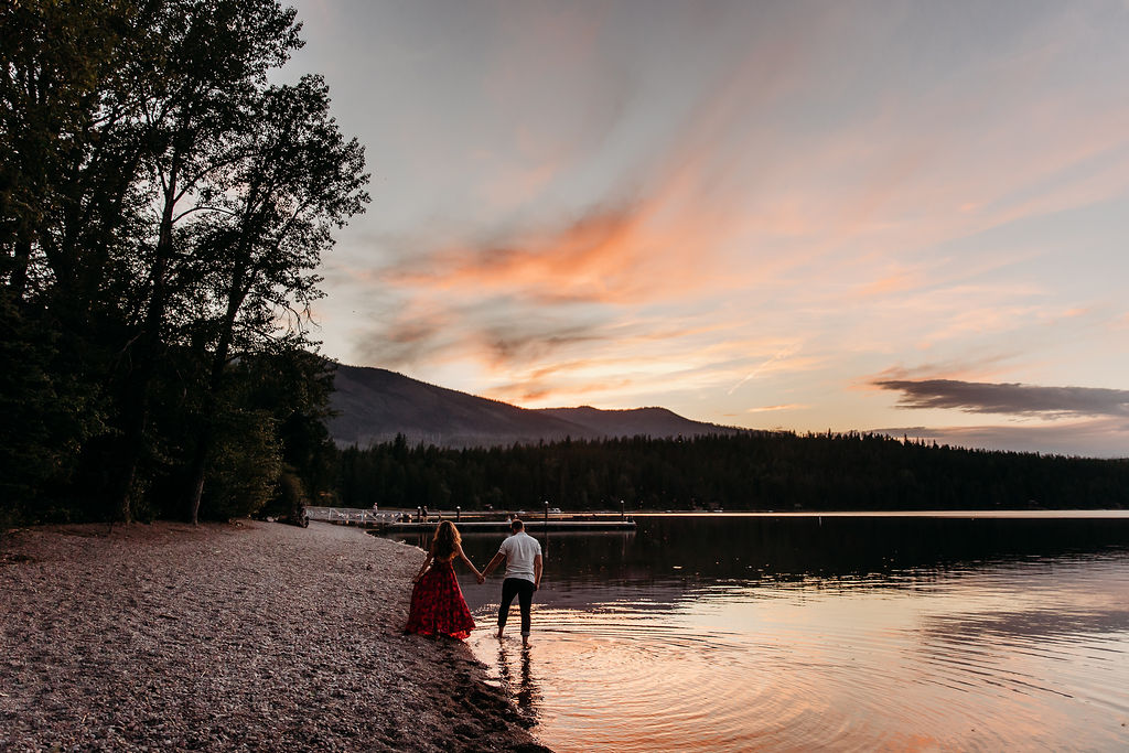 Couple posing for steamy engagement photos in Glacier National Park at Lake McDonald