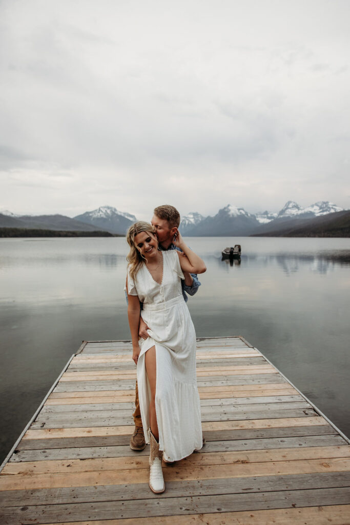 Couple posing for engagement photos in Glacier National Park at Lake McDonald