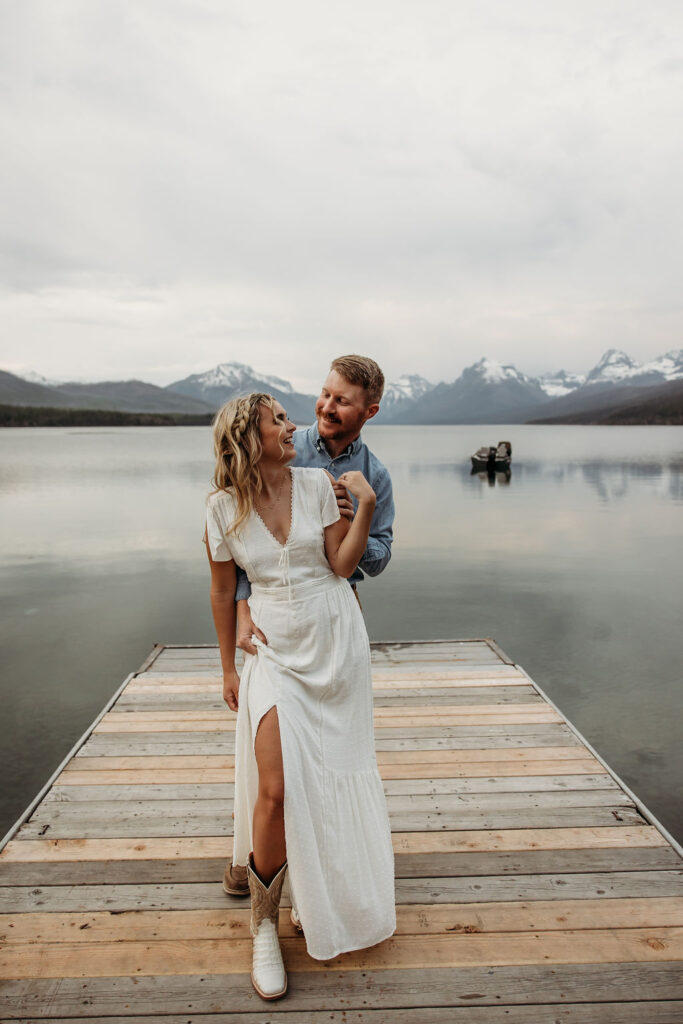 Couple posing for engagement photos in Glacier National Park at Lake McDonald