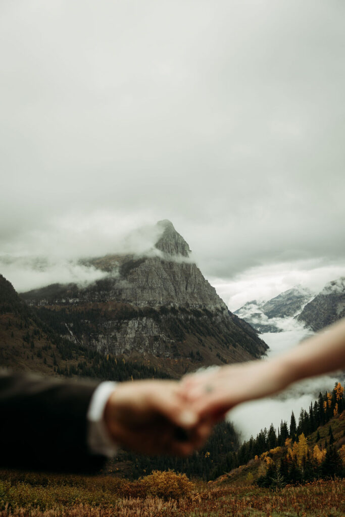 Bride and groom holdings hands with mountains in the background