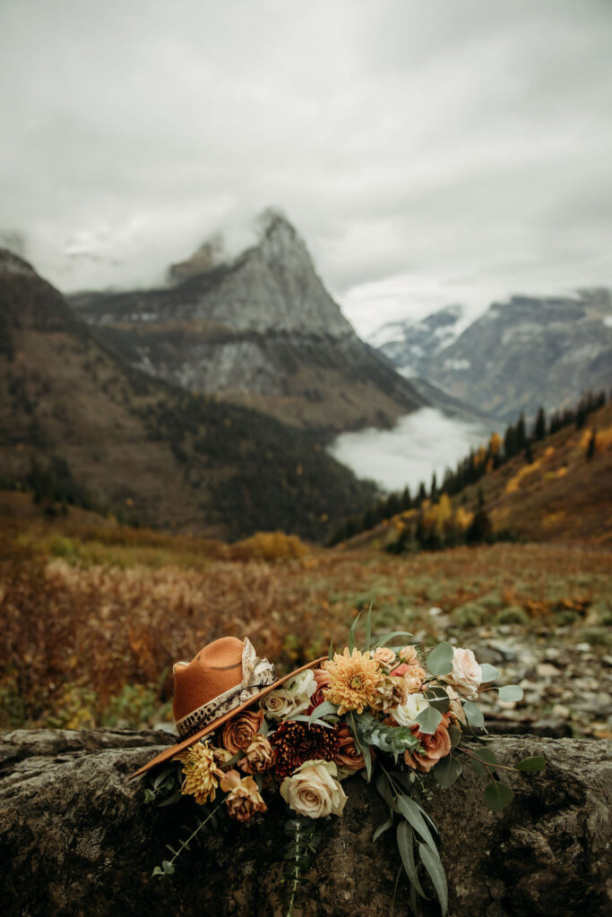 Brides hat and bouquet on a rock in the mountains 