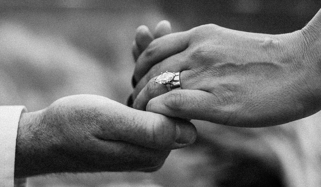 Groom holding brides hand with ring