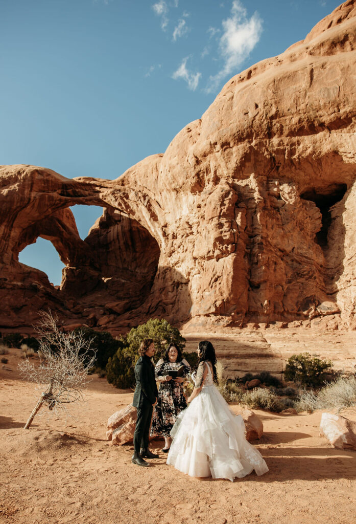 Wedding ceremony taking place in front of a scenic natural arch at Arches National Park 