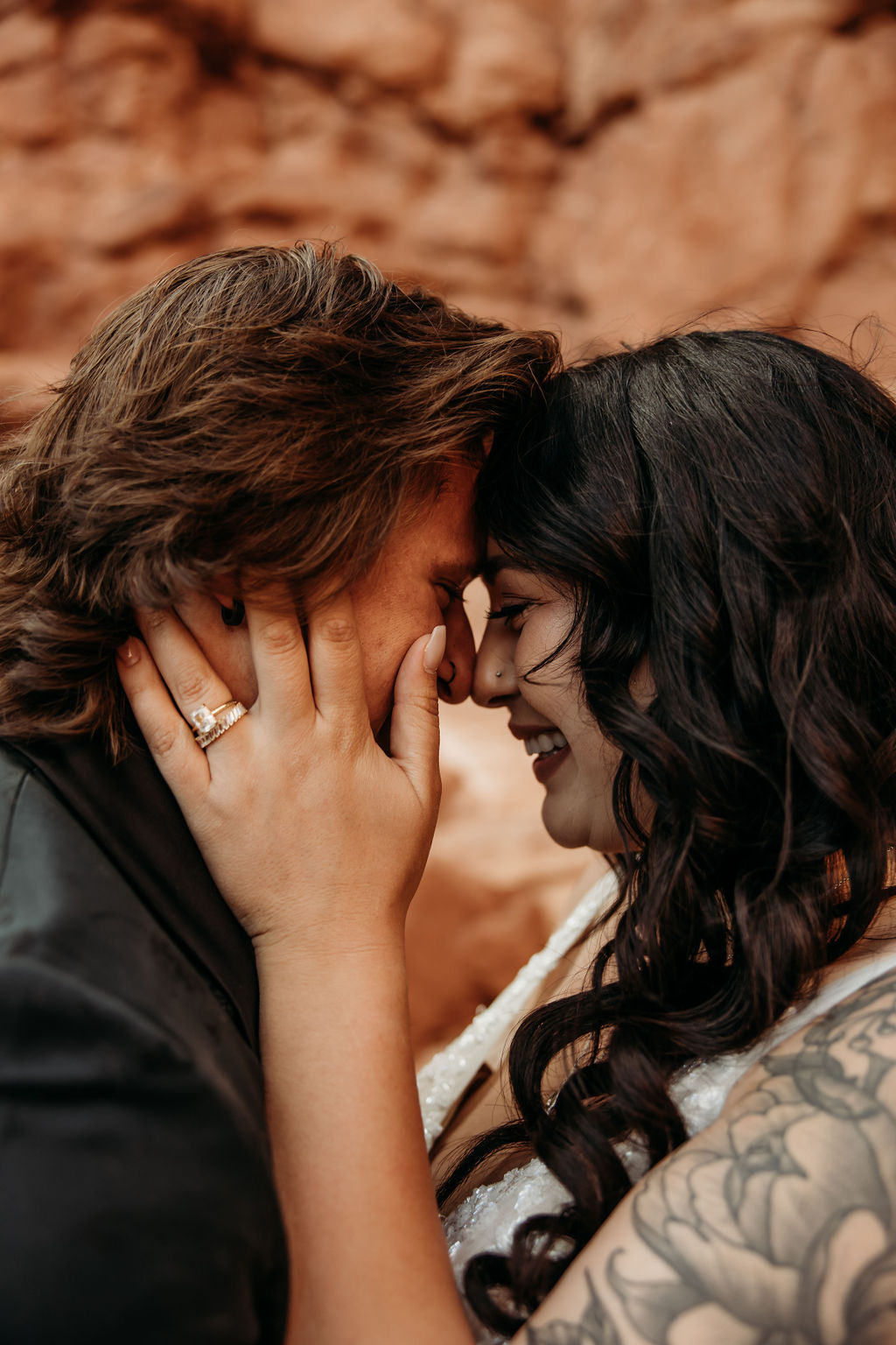 Intimate moment between two people with one gently holding the other's face, smiling closely with affection at Arches National Park