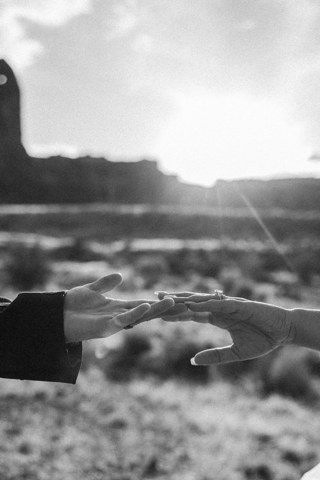 Two hands reaching towards each other against a blurred desert landscape at Arches National Park