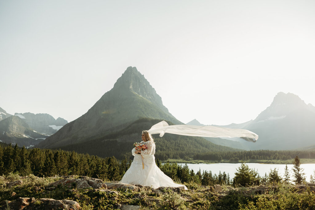 Bride and groom walking hand in hand along a mountain trail in GNP.
