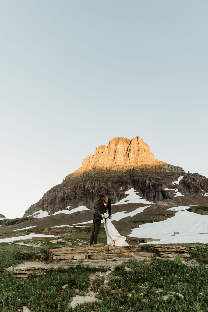 A romantic moment captured as a couple celebrates their elopement in Glacier National Park's rugged beauty.
