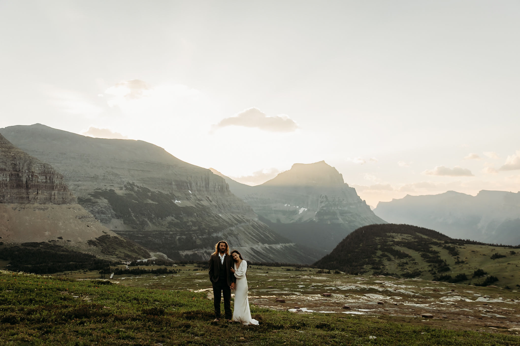 A couple standing together in Glacier National Park, surrounded by stunning mountain views during their adventure elopement.