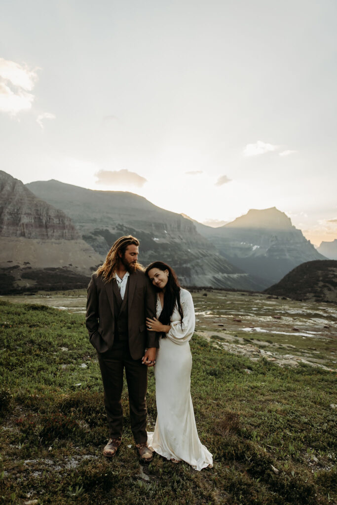 A couple standing together in Glacier National Park, surrounded by stunning mountain views during their adventure elopement.
