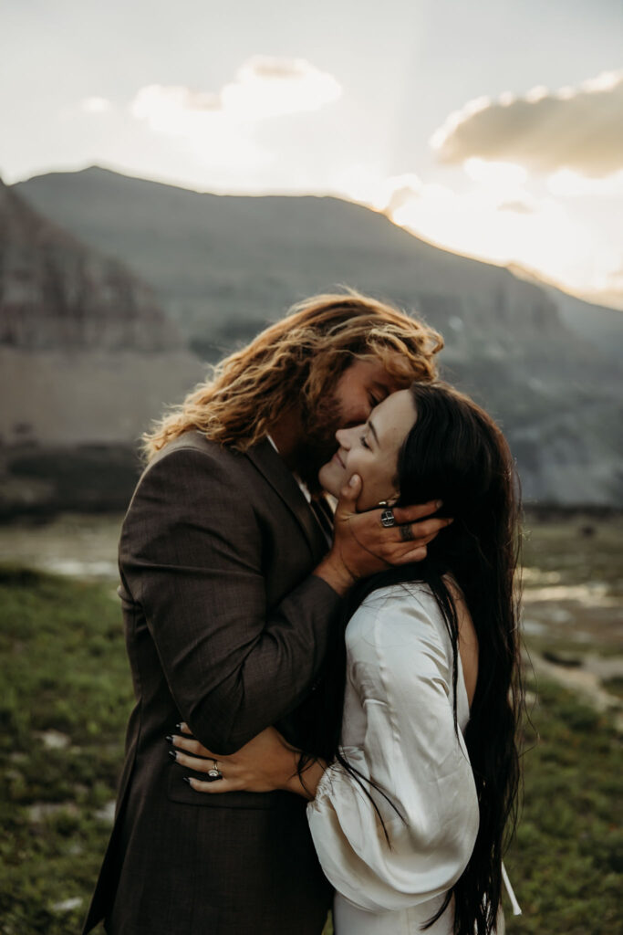 A couple standing together in Glacier National Park, surrounded by stunning mountain views during their adventure elopement.