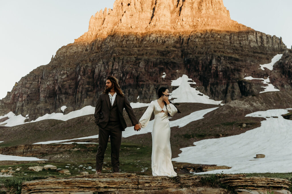 A couple standing together during their adventurous elopement photoshoot in Glacier National Park, Montana, surrounded by stunning natural scenery.
