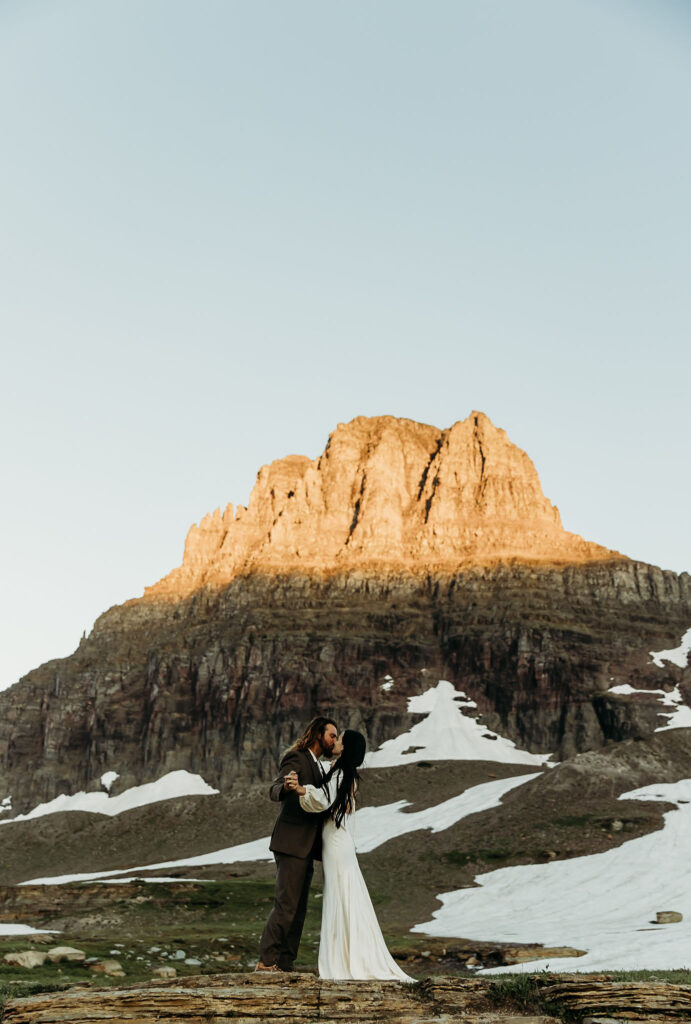 An adventurous pair posing for their elopement photos amidst the breathtaking landscapes of Glacier National Park in Montana.