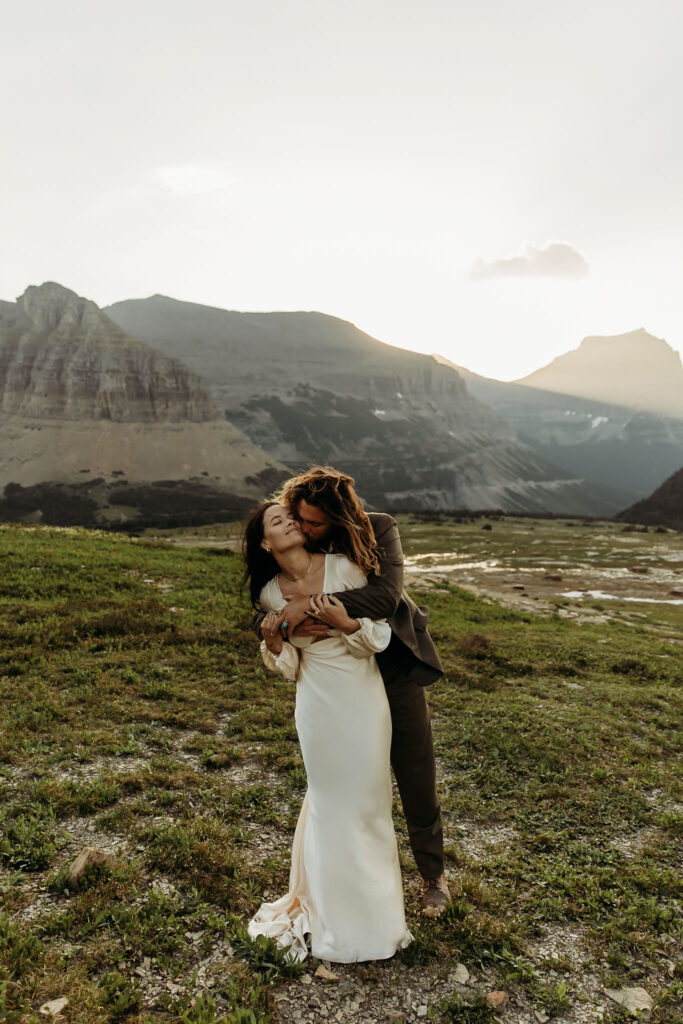 A couple standing together in Glacier National Park, surrounded by stunning mountain views during their adventure elopement.
