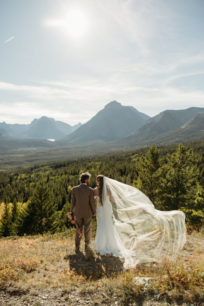 An adventurous couple posing in the scenic landscape of Glacier National Park for their elopement session.
