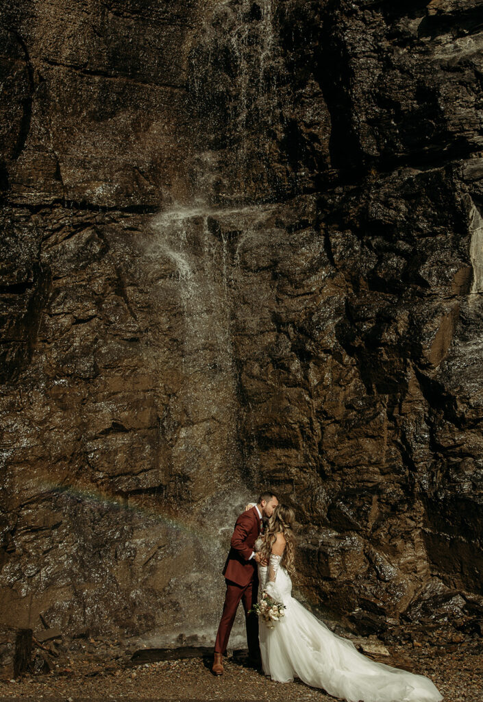 A couple embracing in Glacier National Park, celebrating their destination elopement with stunning mountain views.
