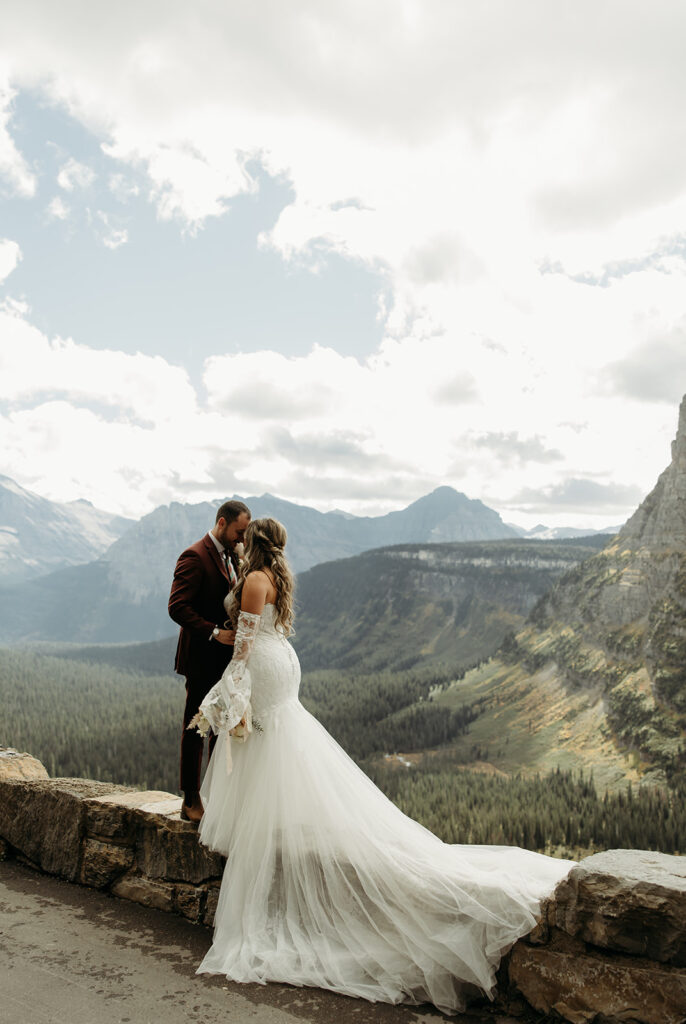 A couple embracing in Glacier National Park, celebrating their destination elopement with stunning mountain views.
