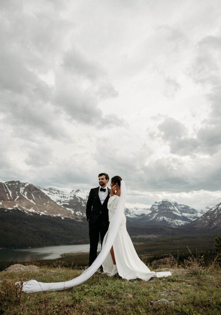 A couple standing together in Glacier National Park, capturing their adventurous destination elopement.
