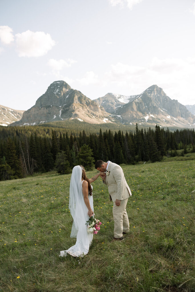 Bride and groom walking through a mountain meadow in Glacier National Park
