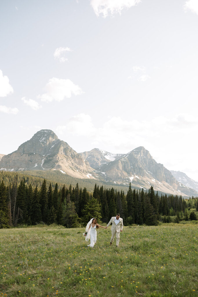Bride and groom walking through a mountain meadow in Glacier National Park
