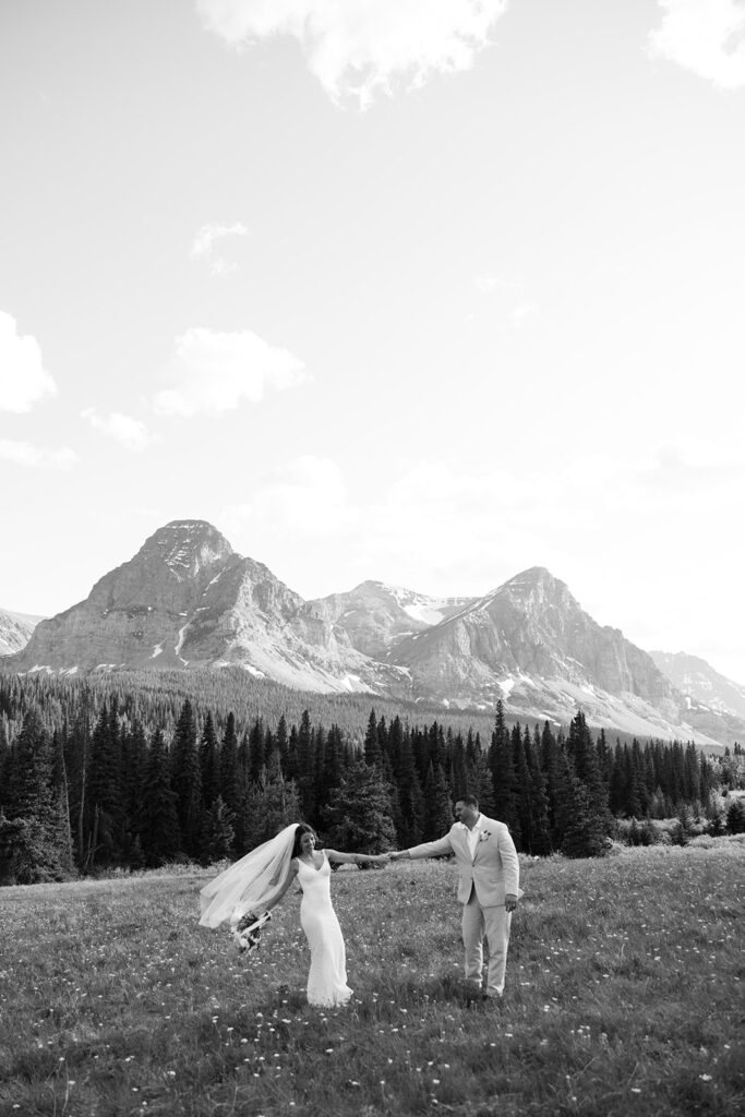 Bride and groom walking through a mountain meadow in Glacier National Park