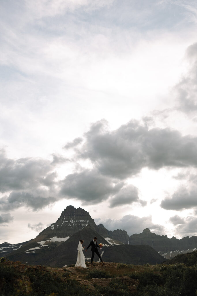 Couple walking through wildflowers at Many Glacier in Glacier National Park.
