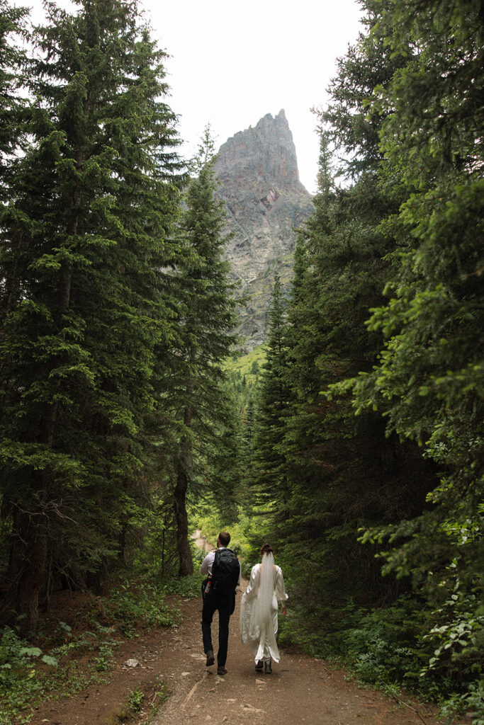 Bride and groom standing by Josephine Lake shoreline surrounded by mountains.
