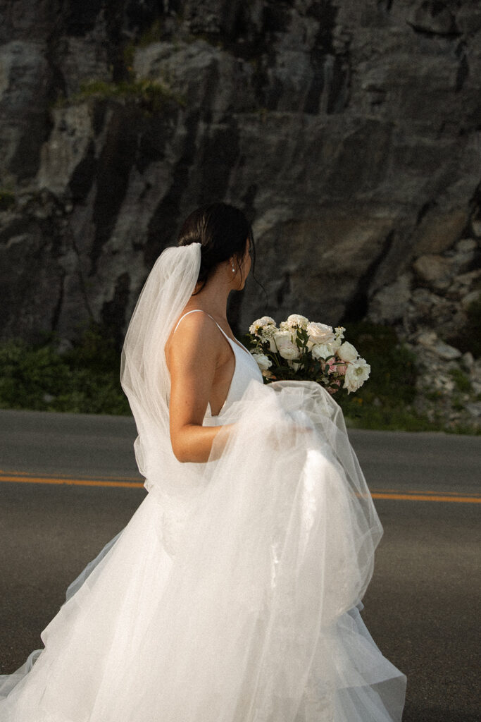 Couple standing together along Going to the Sun Road with mountains in the background

