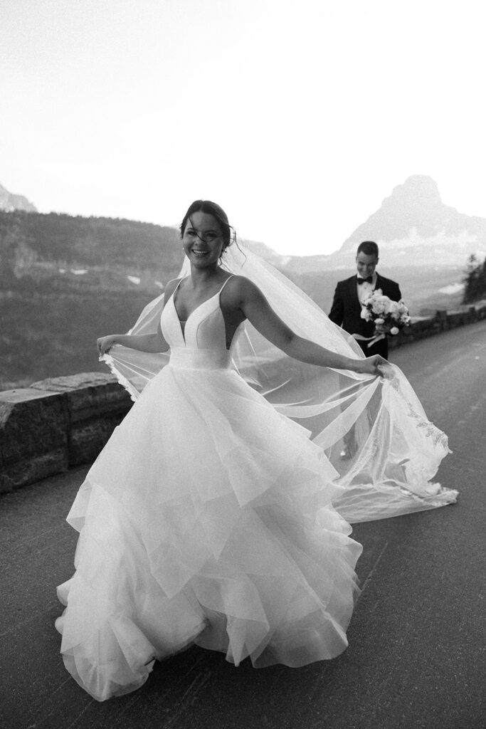Couple standing together along Going to the Sun Road with mountains in the background
