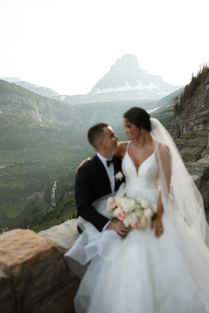 Couple standing together along Going to the Sun Road with mountains in the background
