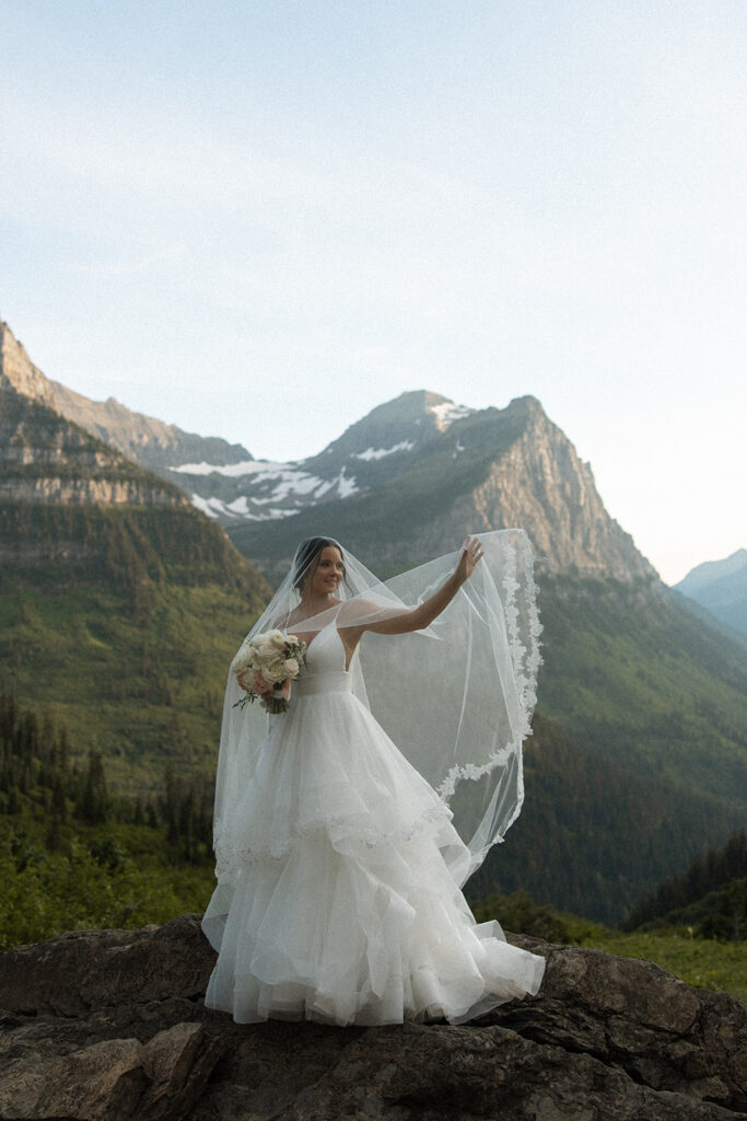 Couple standing together along Going to the Sun Road with mountains in the background
