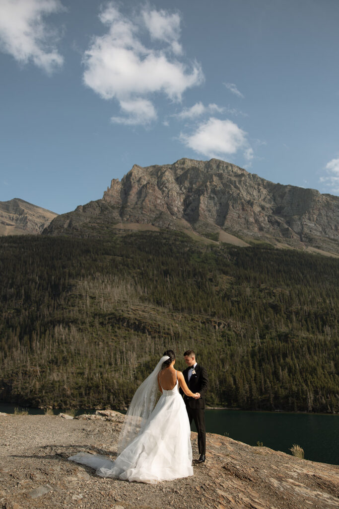 Bride and groom holding hands during their Sun Point ceremony in Glacier National Park
