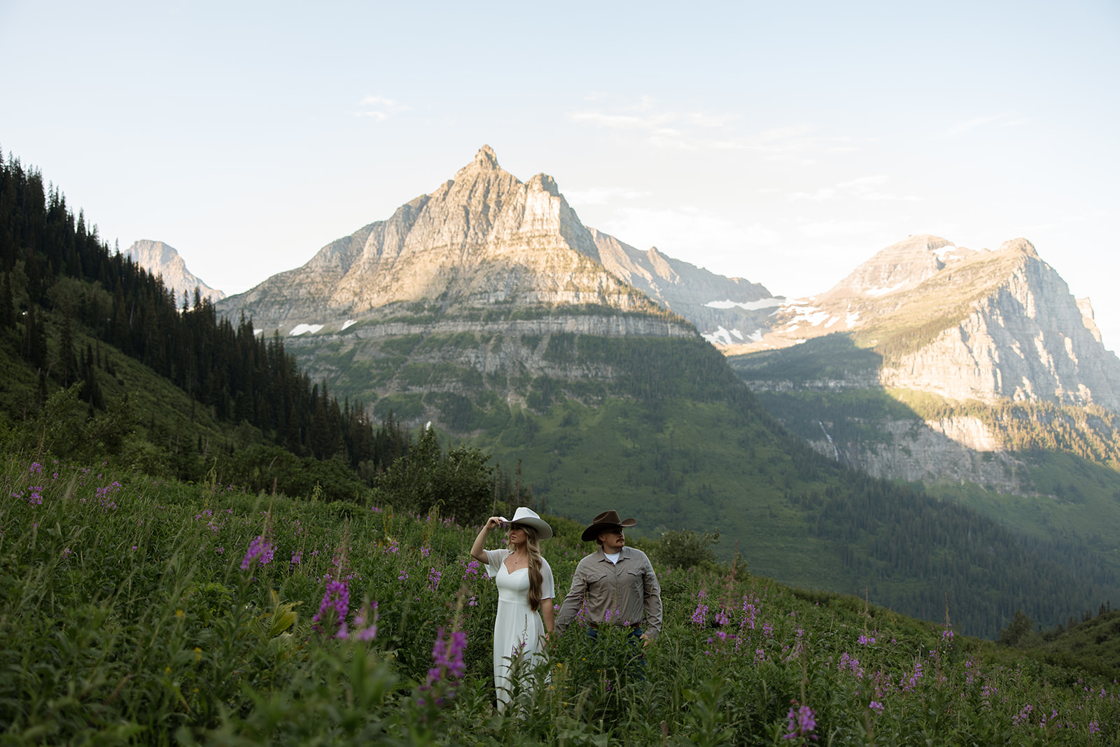 Couple laughing together during a sunrise fun engagement shoot along the Going-to-the-Sun Road in Glacier National Park.