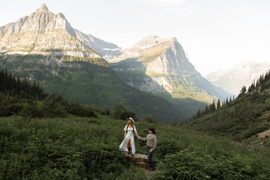 Couple laughing together during a sunrise fun engagement shoot along the Going-to-the-Sun Road in Glacier National Park.
