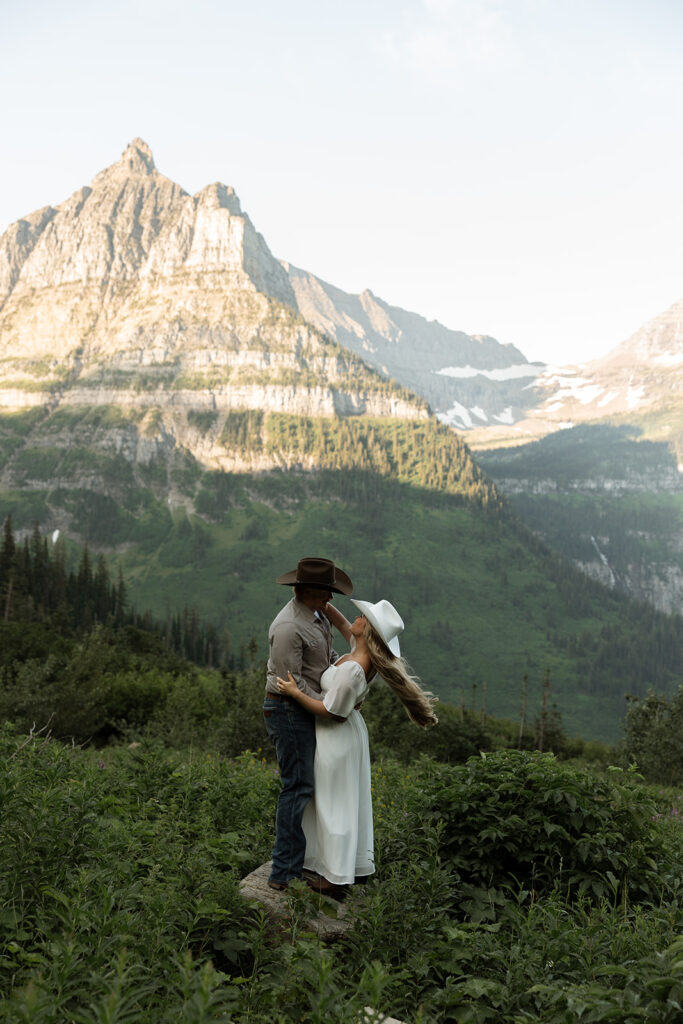Couple laughing together during a sunrise fun engagement shoot along the Going-to-the-Sun Road in Glacier National Park.
