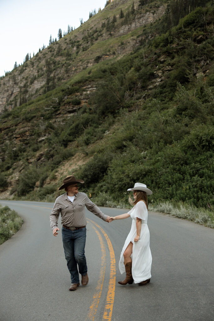 Couple laughing together during a sunrise fun engagement shoot along the Going-to-the-Sun Road in Glacier National Park.
