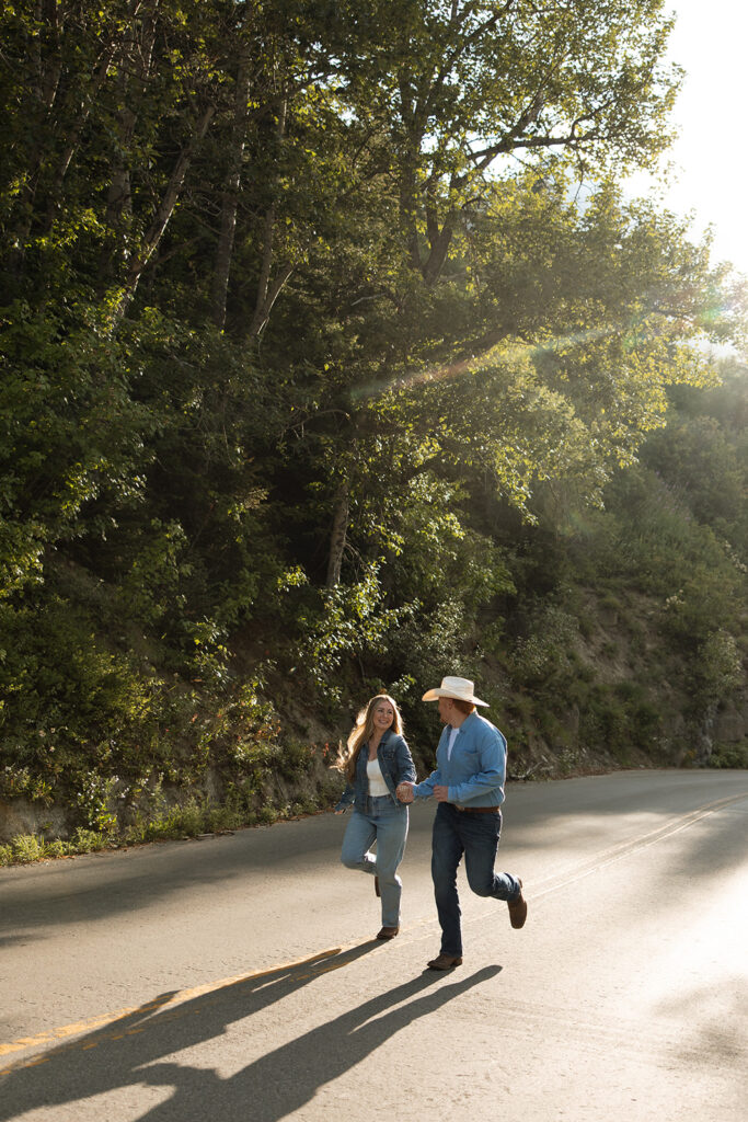 Couple laughing together during a sunrise fun engagement shoot along the Going-to-the-Sun Road in Glacier National Park.
