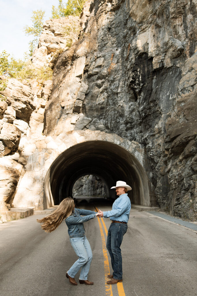 Couple laughing together during a sunrise fun engagement shoot along the Going-to-the-Sun Road in Glacier National Park.
