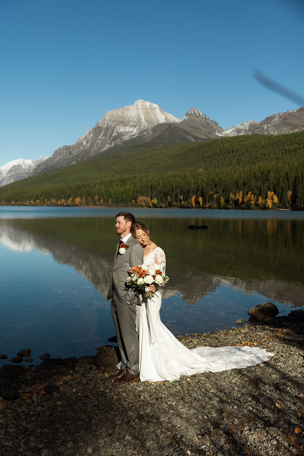Couple standing on the shore of Bowman Lake in Montana during their Glacier National Park elopement