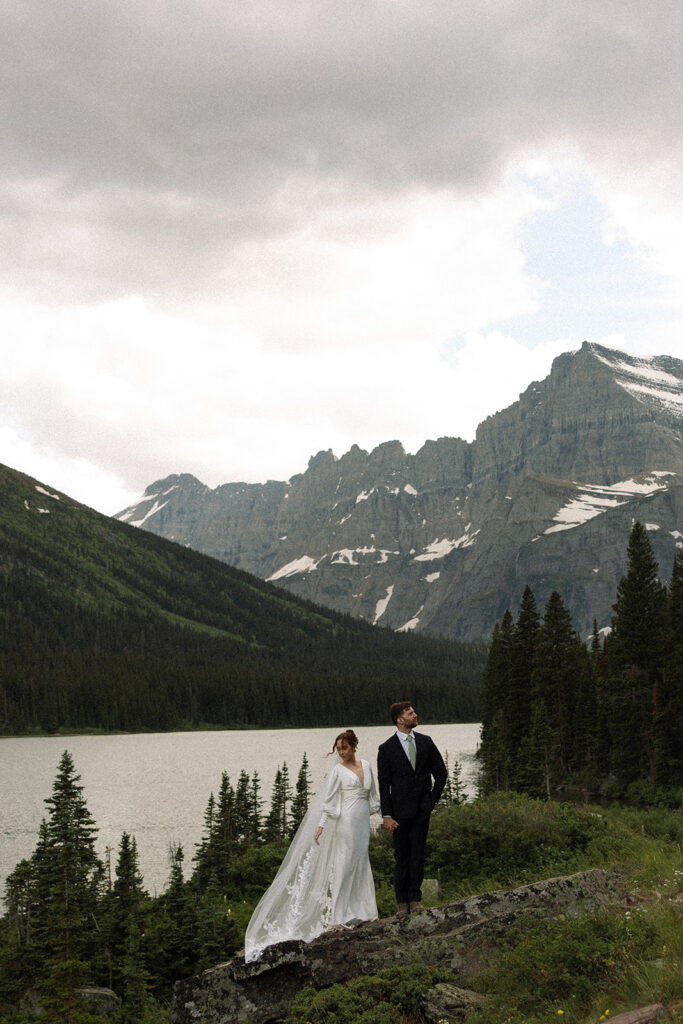 Sunrise elopement photos at Swiftcurrent Lake featuring calm water, glowing mountain peaks, and quiet morning light in Glacier National Park.
