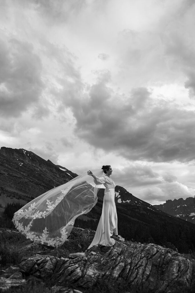 Couple sharing an intimate sunrise elopement at Many Glacier with alpenglow lighting the mountains behind them in Glacier National Park.

