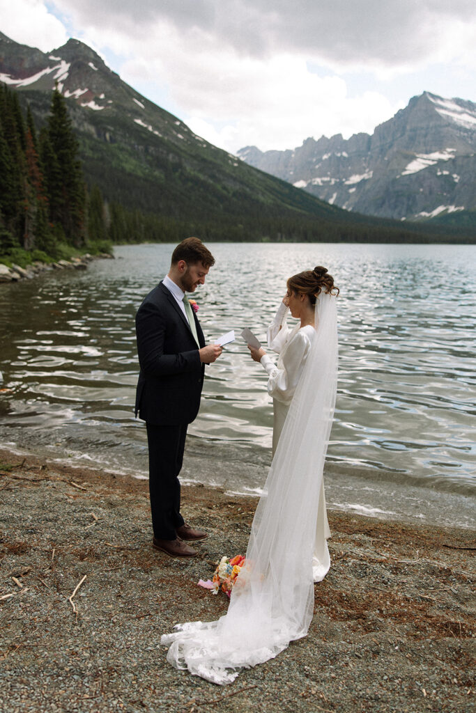 Sunrise elopement photos at Swiftcurrent Lake featuring calm water, glowing mountain peaks, and quiet morning light in Glacier National Park.
