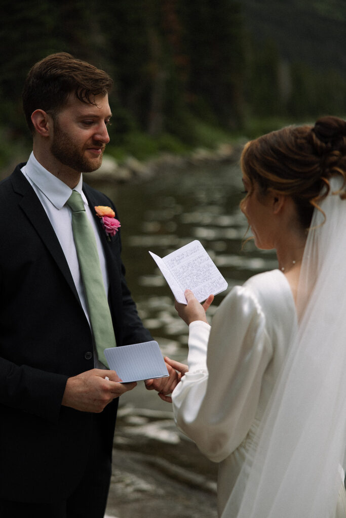 Couple sharing an intimate sunrise elopement at Many Glacier with alpenglow lighting the mountains behind them in Glacier National Park.

