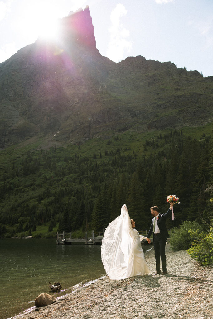Romantic sunrise elopement moment at Many Glacier with turquoise lake reflections and soft pastel skies in Glacier National Park.
