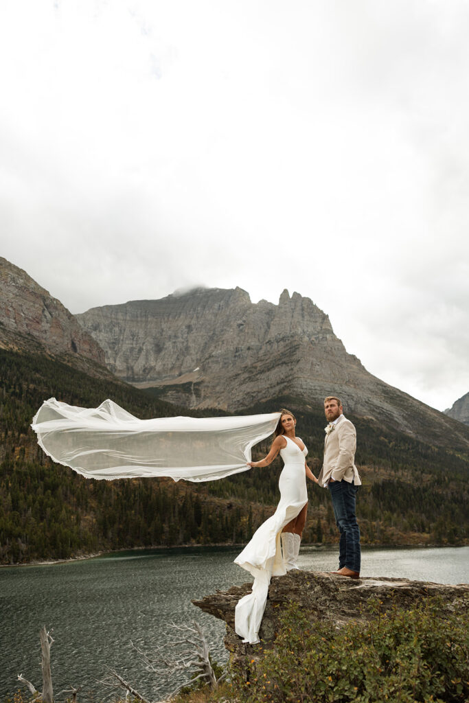 Romantic elopement portraits in Glacier National Park with dramatic clouds and layered mountain scenery