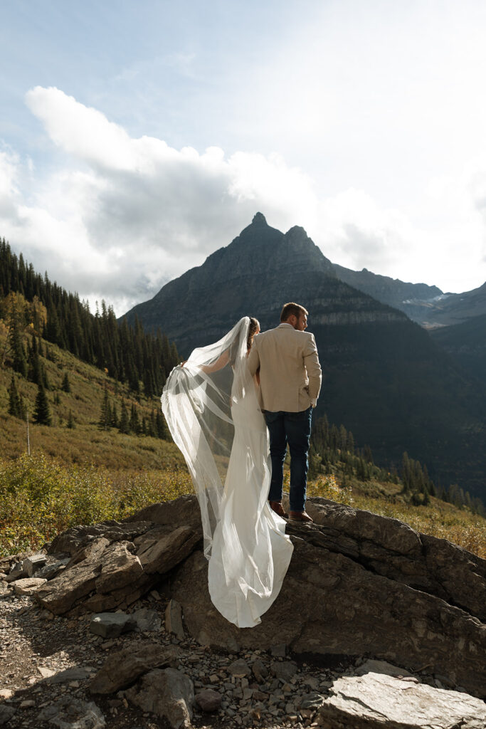 Couple eloping in Glacier National Park at sunrise with mountain views and soft golden light