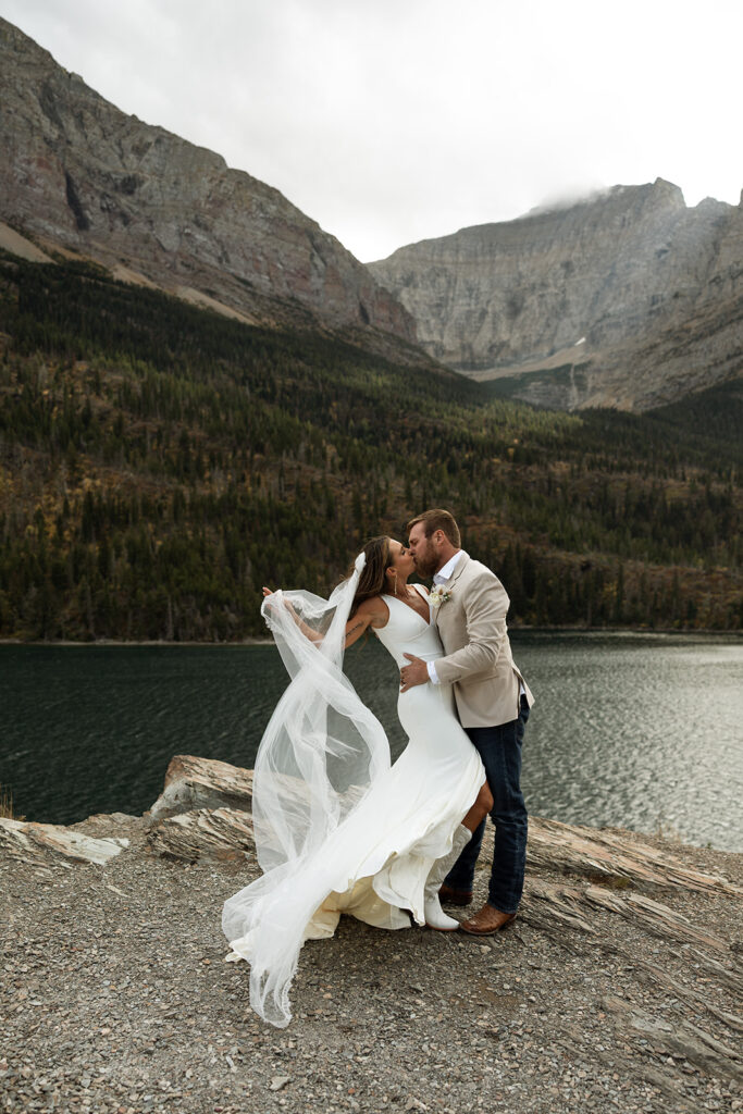 Couple eloping in Glacier National Park at sunrise with mountain views and soft golden light
