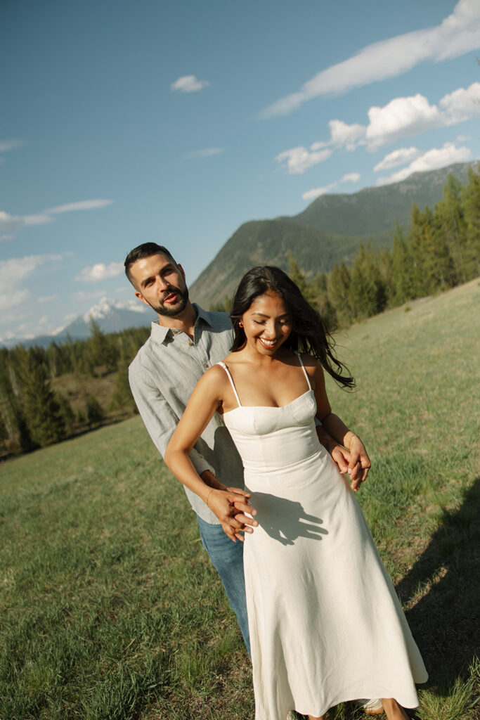 Couple embracing with mountains and fresh greenery in the background at Glacier National Park
